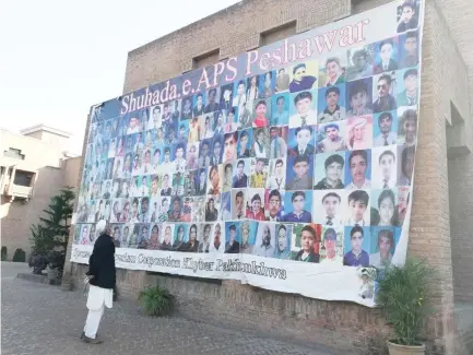  ??  ?? A man looks at a banner displaying pictures of the students who were killed during the APS massacre in Peshawar, Pakistan. (AN photo)