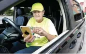  ?? AP PHOTO/MARK HUMPHREY ?? Lyft driver Joni Bicknese checks her phone app between riders last week in Nashville.