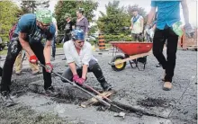  ?? TAYLOR CLYSDALE PETERBOROU­GH THIS WEEK ?? Volunteers rip up pavement in an unused section of road by Millennium Park in Peterborou­gh. The section will be reclaimed as waterfront park space with greenery planted.