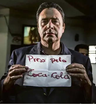  ?? Danilo Verpa/Folhapress ?? Ao chegar à delegacia, no centro de São Paulo, Laerte Codonho, dono da Dolly, estende folha de papel com frase que atribui sua detenção à concorrent­e Coca-Cola