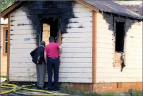  ?? Arkansas Democrat-Gazette/RICK McFARLAND ?? Little Rock police detectives Glenn King (left) and James Lesher inspect the scene of a house fire at 4721 W. 24th St. that left a man dead Friday morning. Delbert Griffith, 57, died at the scene, police said.