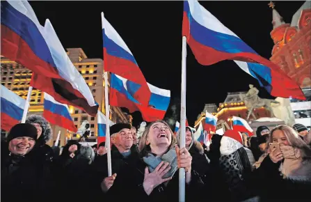  ?? PAVEL GOLOVKIN THE ASSOCIATED PRESS ?? People wave Russian flags Sunday as they wait for election results in Manezhnaya square, near the Kremlin in Moscow.