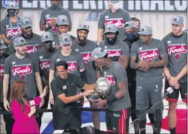  ?? MARK J. TERRILL— THE ASSOCIATED PRESS ?? Miami Heat head coach Erik Spoelstra, center left, hands the Eastern Conference trophy to Bam Adebayo as they celebrate their NBA conference final playoff win over the Boston Celtics with the Eastern Final trophy Sunday in Lake Buena Vista, Fla.