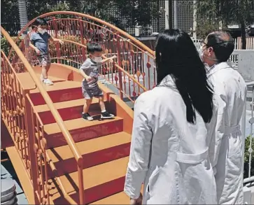  ?? Wesley Lapointe Los Angeles Times ?? IT WAS PLAYTIME on Tuesday outside Children’s Hospital Los Angeles, as Callum Diaz-Cheng, 3, left, and Aevin Lee, 2, waited to be vaccinated, while their parents Dr. Jennifer Su and Dr. Andrew Cheng looked on.