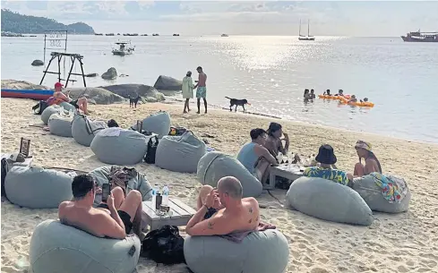  ?? ?? VISITORS RETURN: Tourists relax by the beach on Koh Tao in Surat Thani. Arrivals to the kingdom have dropped since the Test & Go programme was suspended recently, prompted by a resurgence of Covid-19 caseloads caused by the fast-spreading Omicron variant.