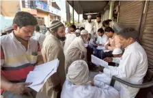  ?? AP ?? People check for their names in the voters’ list as they arrive to vote in Nahal village near Meerut on Friday.