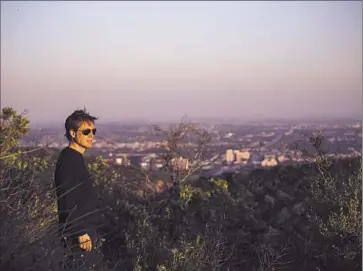  ?? Jay L. Clendenin Los Angeles Times ?? NICOLAS BERGGRUEN walks along a peak on the 450 acres he purchased in the Sepulveda Pass. On the one-time landfill for the city, he plans to build the headquarte­rs for a think tank that bears his name.