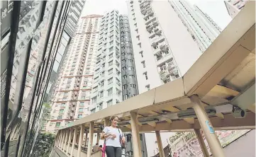  ??  ?? A woman walks down a path, as high-rise residentia­l buildings installed with air conditioni­ng units are seen in the background, in Hong Kong’s Mid-Levels district. Calls to restrict domestic maids from using air conditioni­ng in their employers’ homes...