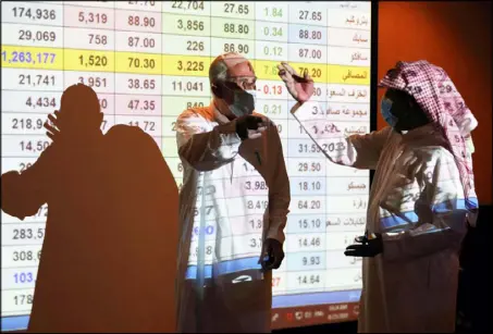  ??  ?? مستثمرون سعوديون يتابعون أسعار الأسهم على شاشة إلكترونية في بورصة «تداول» في الرياض