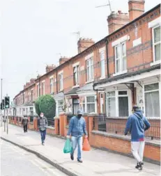  ??  ?? Ciudadanos usan mascarilla­s mientras caminan por la calle en el barrio de North Evington, en Leicester.
