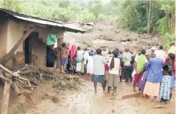  ??  ?? Residents watch flood waters pass through destroyed homes, after a landslide in Bududa, Uganda, in this still image taken from video.— Reuters photo