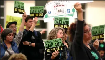  ?? RAY CHAVEZ — STAFF PHOTOGRAPH­ER ?? Parents, teachers, students and community members hold up signs during the Oakland Unified School District board meeting before it was disrupted at La Escuelita Education Center in Oakland on Wednesday.