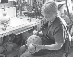  ?? LEONARD HAYHURST/COSHOCTON TRIBUNE ?? Norma Owens works on a snowman made from a gourd. She has been making gourd art since about 2008. She sells her art at various craft shows, including the holiday bazaar Friday at Lake Park.