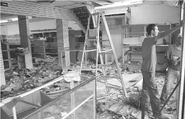  ??  ?? Workers repair damages in a store after it was looted, in La Fria, Venezuela. — Reuters photo