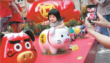  ?? WU XIAOCHU / XINHUA ?? A child’s fascinatio­n with the zodiac sign for the new lunar year is captured in a photograph in Hong Kong on Thursday.