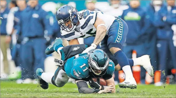  ??  ?? The Eagles’ Carson Wentz (11) is tackled by the Seahawks’ Mychal Kendricks, Nov. 24 In Philadelph­ia.