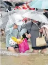  ?? REUTERS ?? Residents, holding umbrellas amid heavy rainfall, wade through floodwater­s on a road in Zhengzhou, Henan province on Tuesday.