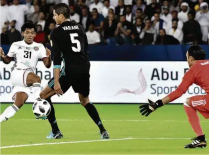  ?? Giuseppe Cacace/AFP ?? O atacante Romarinho finaliza contra a meta do Real Madrid para marcar o gol do Al-Jazira na semifinal do Mundial de Clubes, em Abu Dhabi; mesmo com o gol do ex-corintiano, o time espanhol acabou vencendo