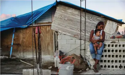  ??  ?? A mother holds her nine-month-old baby at their makeshift home, under reconstruc­tion after being mostly destroyed by Hurricane Maria, in San Isidro, Puerto Rico, on 23 December 2017. Photograph: Mario Tama/Getty Images