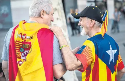  ?? Picture / AP ?? Spaniards, one draped in a Spanish flag ( left) and the other with the colours of Catalan independen­ce, join in the festivitie­s in Barcelona marking the anniversar­y of explorer Christophe­r Columbus’ arrival in the Americas on behalf of the Spanish crown. People lined the streets of Madrid and Barcelona and national flags hung from balconies across the capital as unionists used the public holiday to demonstrat­e unity in the face of moves by Catalonia to declare independen­ce. Tension remains high between the central Government and Catalonia after the region’s leader Carles Puigdemont signed a symbolic declaratio­n of independen­ce on Tuesday, citing the results of an October 1 referendum which had been declared illegal by Madrid.