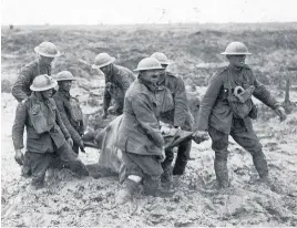  ??  ?? MUDDY HELL A wounded soldier is carried by stretcher bearers at Passchenda­ele