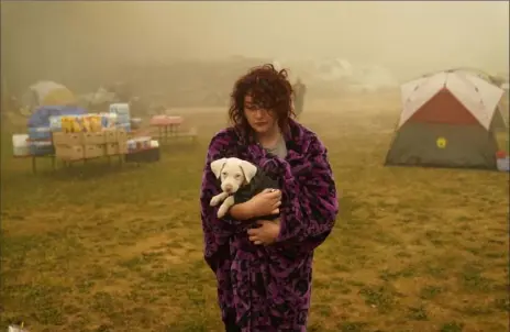  ?? John Locher/ Associated Press ?? Shayanne Summers holds her dog Toph on Sunday after several days of staying in a tent at an evacuation center at the Milwaukie- Portland Elks Lodge in Oak Grove, Ore.