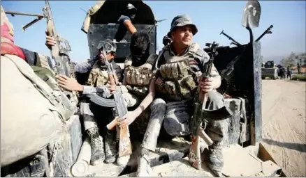  ?? AFP ?? Members of the Iraqi government forces sit in the back of their vehicle during an operation, backed by air support from the US-led coalition, in Fallujah’s southern Shuhada neighbourh­ood to retake the area from the Islamic State group on June 15.