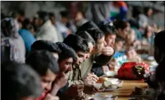  ?? AP Photo/AMel eMrIc ?? Migrants eat lunch in the abandoned building of a former hotel in the western Bosnian town of Bihac.