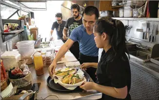  ?? RALPH BARRERA / AMERICAN-STATESMAN ?? Tebi Nguyen (center) and Trinh Nguyen prepare bahn mi sandwiches at the Saigon le Vendeur food trailer on East Seventh Street. A report by the Federal Reserve Bank of Dallas shows the state’s service sector expanded at a faster rate in May than in April.