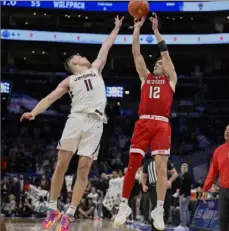  ?? Nick Wass/Associated Press ?? North Carolina State guard Michael O’Connell shoots over Virginia guard Isaac McKneely to tie the game at 58 and send the game into overtime Friday in a semifinal of the Atlantic Coast Conference tournament in Washington, D.C.