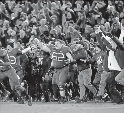  ?? Patrick Semansky / The Associated Press ?? Army players and coaches run onto the field after defeating Navy 21-17 on Saturday in Baltimore. The win ended a 14-game skid for Army.