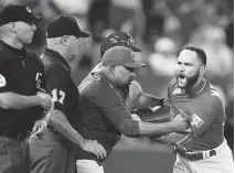  ?? FRANK GUNN/THE CANADIAN PRESS ?? Catcher Russell Martin is held back by Blue Jays coaches as he erupts over home plate umpire Vic Carapazza’s decision to eject him in the 13th inning on Friday.