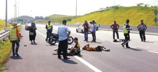  ??  ?? The injured cyclists lying on the highway shortly after the incident yesterday as officials secure the area.