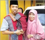  ?? EKO HENDRI/JAWA POS ?? INGIN TAMBAH: Adi Wisnugraha menggendon­g Fayyadh Zhafri Nugraha didampingi Siti Maimunah.