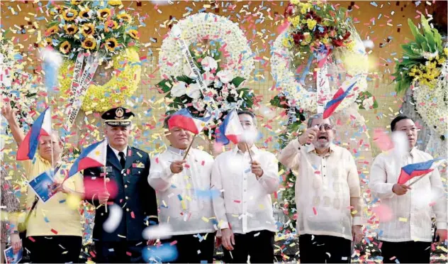  ?? Agence France-presse ?? ↑
Officials raise flags after the wreath laying ceremony in front of the People Power Monument on Epifanio de los Santos Avenue in Quezon City, on Sunday.