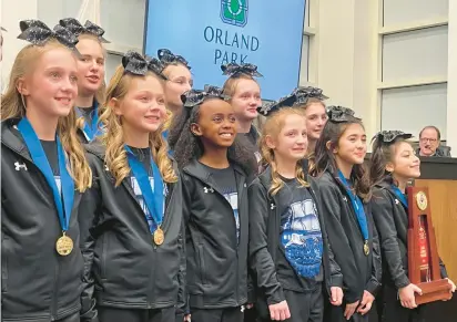  ?? JEFF VORVA/DAILY SOUTHTOWN PHOTOS ?? Members of the St. Michael School cheer squad are honored in February at an Orland Park Village Board meeting after they won the program’s 20th ICCA state title.