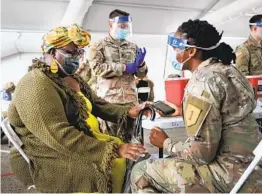  ?? JOE RAEDLE GETTY IMAGES ?? A U.S. Army soldier prepares to immunize Tangela C. Mitchill with the COVID-19 vaccine at the Miami Dade College North Campus in North Miami, Fla.
