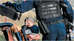  ?? AP ?? Framed by heavily armed Mexican authoritie­s, relatives of the LeBaron family mourn at the site where nine people related to the extended LeBaron family were slaughtere­d when cartel gunmen ambushed three SUVs along a dirt road near Bavispe, at the SonoraChih­uahua border.