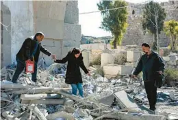  ?? LOUAI BESHARA/GETTY-AFP ?? A woman is helped as she walks through rubble in the aftermath of a reported Israeli airstrike Sunday in Damascus, Syria, that caused at least five deaths.