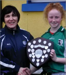  ??  ?? Scoil Naomh Molaise captain Tara Casserly receives the shield from Mary Curley, chairperso­n of the Cumann na mBunscol.