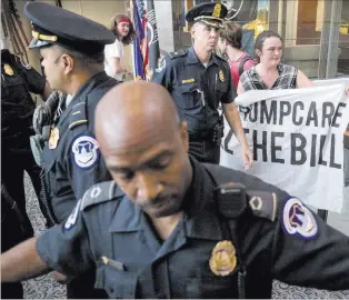  ?? Andrew Harnik ?? The Associated Press Capitol Hill police officers prepare Monday to arrest a group protesting the Republican health care bill outside the offices of Sen. Dean Heller, R-nev., in Washington.