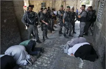  ??  ?? Palestinia­ns pray as Israeli border police officers stand guard at the Lion’s Gate in Jerusalem’s Old City on Tuesday. Dozens of Muslims have prayed in the street outside a major Jerusalem shrine, heeding a call by clerics not to enter the site until a...