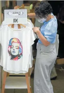  ??  ?? Una mujer mira una camiseta en la tienda Skaner Shop.