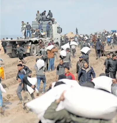  ?? YOUSEF ALROZZI (FAO) / REUTERS ?? A la izquierda, una familia palestina repartía cebada entre sus ovejas el día 8 en Rafah, en el sur de la Franja. Arriba, palestinos cargaban sacos de harina en febrero de 2024.