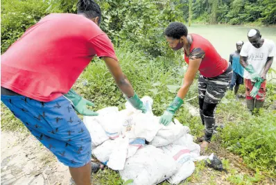  ?? FILE PHOTOS ?? Residents in Kent Village packing dead fish into bags after removing them from the Rio Cobre after a massive fish kill in August 2021.