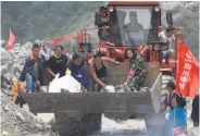  ?? Han Guan Ng / Associated Press ?? Volunteers deliver supplies at the site of the landslide in Xinmo in southweste­rn China.