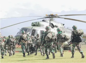  ??  ?? Indonesian military soldiers prepare to board a helicopter from Wamena to retrieve the bodies of the constructi­on workers killed in Nduga. — AFP photos