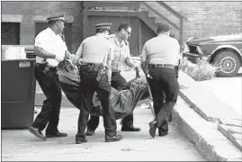  ?? PHIL GREER/CHICAGO TRIBUNE ?? Chicago police officers remove the body of man at the Sutherland Hotel in the 4600 block of South Drexel Boulevard on July 18, 1995.