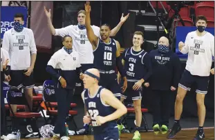  ?? Associated Press ?? Back in the tournament: The Utah State bench reacts as guard Brock Miller (22) sinks a 3-point shot during the first half of an NCAA college basketball game against San Diego State in the championsh­ip of the Mountain West Conference men's tournament Saturday in Las Vegas. The Aggies face Texas Tech in the opening round of the NCAA Tournament on Friday.