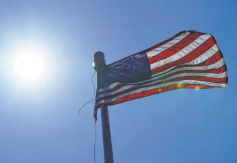  ?? Ted S. Warren / Associated Press ?? A U.S. flag flies in downtown Seattle. Hundreds of heatrelate­d deaths have been confirmed in ordinarily cool Oregon, Washington and British Columbia.